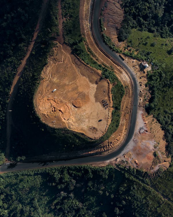 Aerial view of a winding road next to a quarry amidst lush greenery, showing typical corridor mapping terrain
