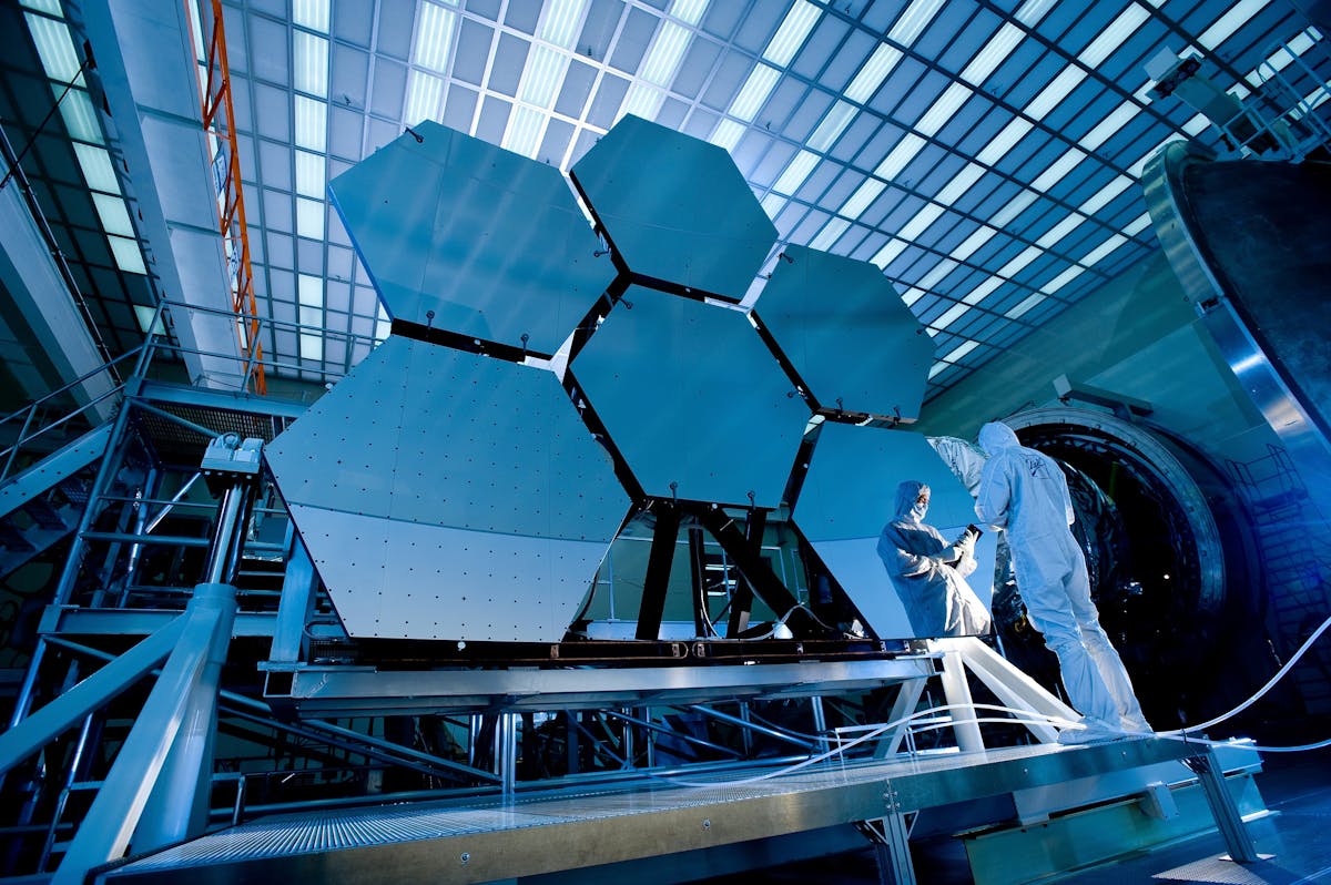 Technician in cleanroom inspecting advanced hexagonal mirror assembly demonstrating precision engineering expertise