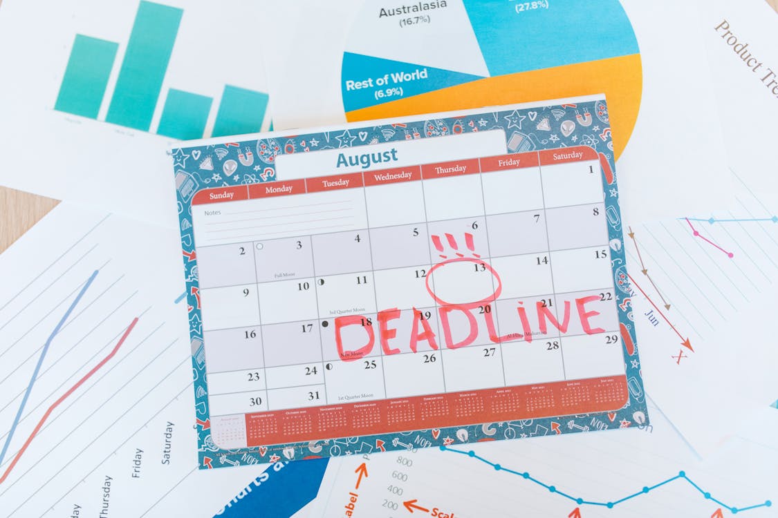 Calendar page with DEADLINE written in red, resting on top of charts and financial graphs