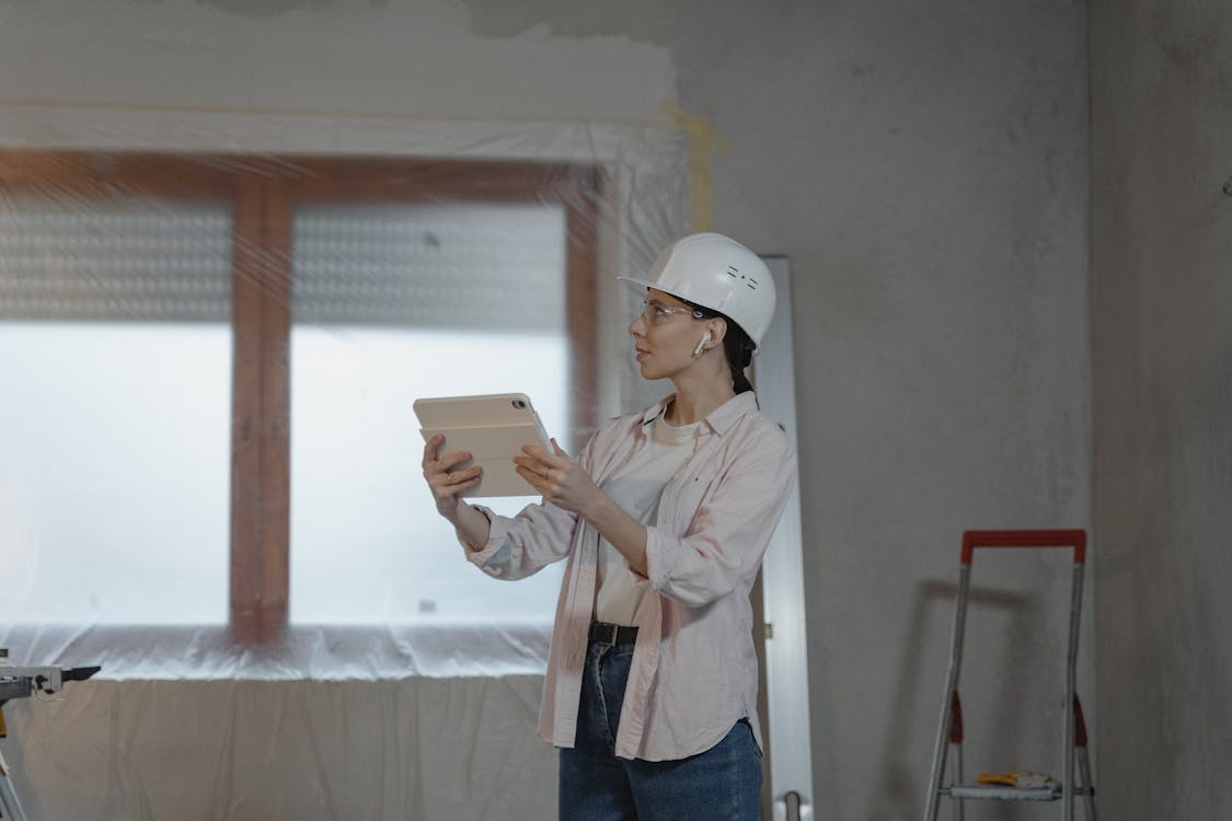 Female engineer in hard hat and safety vest using a digital tablet at a construction site