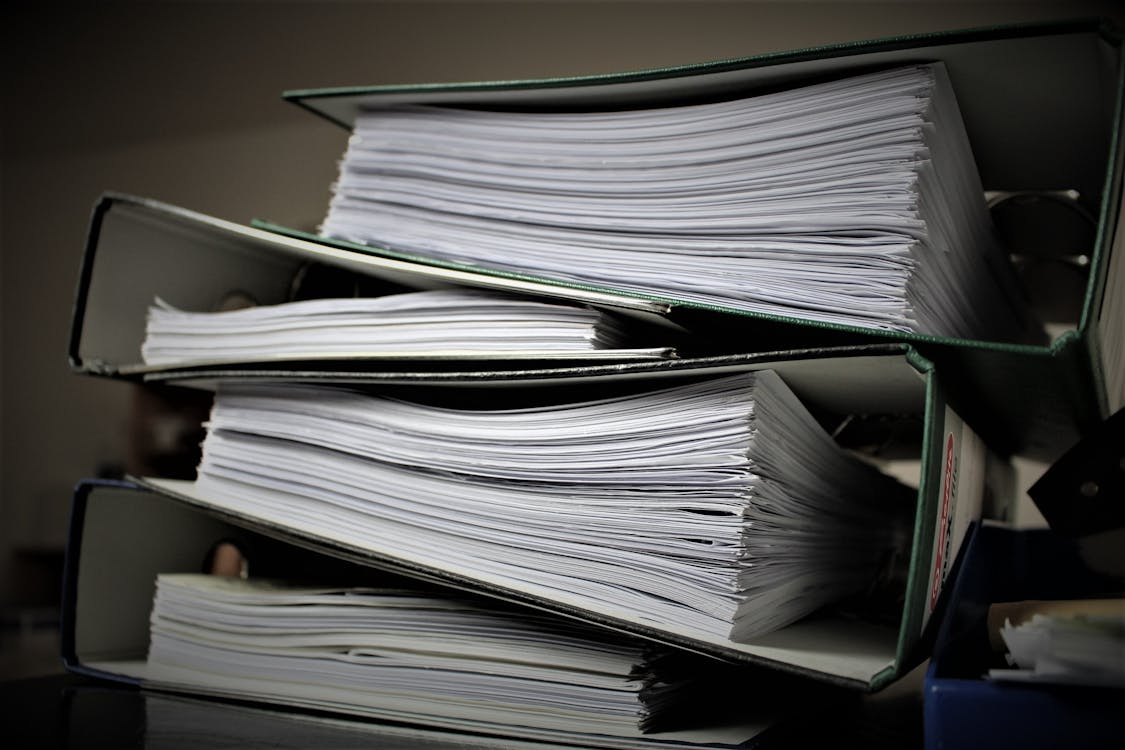 Overflowing binders and stacked documents representing version control challenges