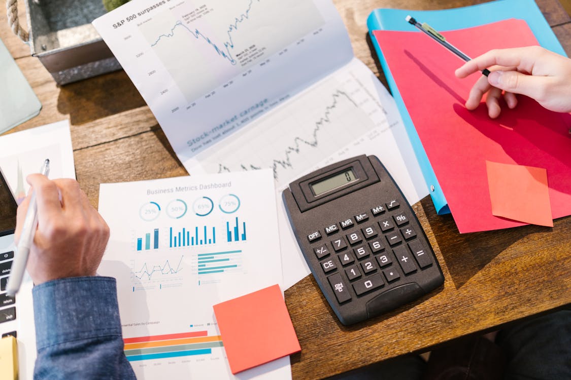 Financial documents with charts, a calculator, and business metrics on an office desk