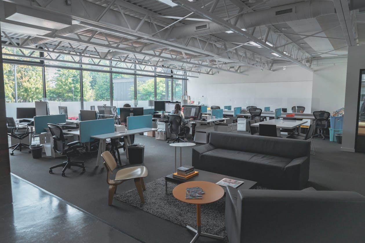 Large open-plan commercial office space with exposed steel trusses and multiple workstations