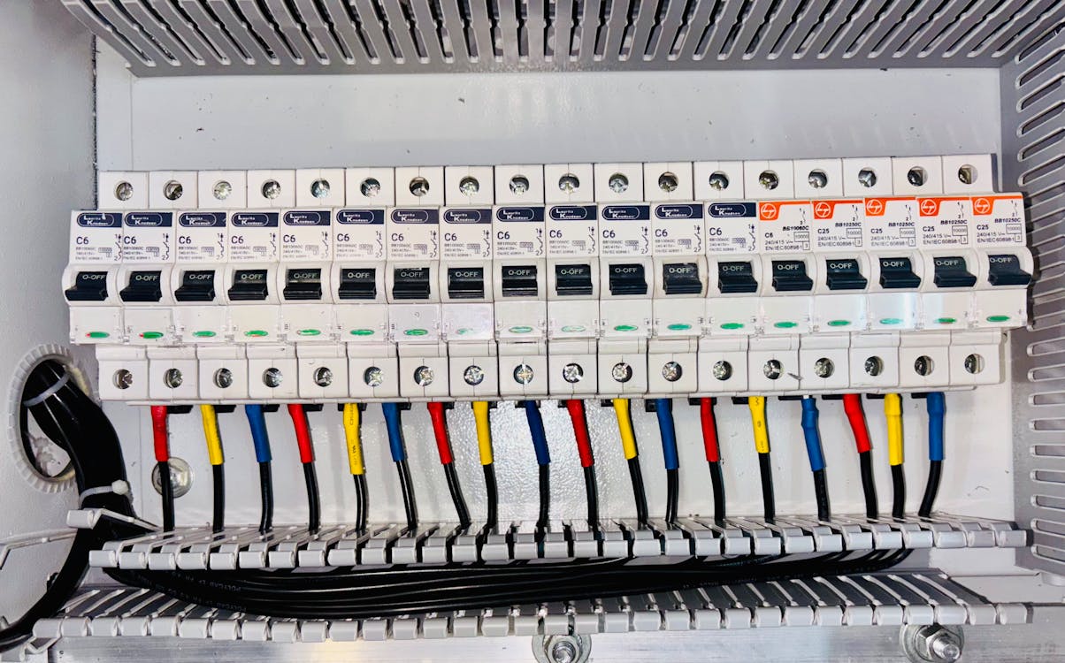 Electrical circuit breaker panel with color-coded wiring and labeled switches in a commercial building