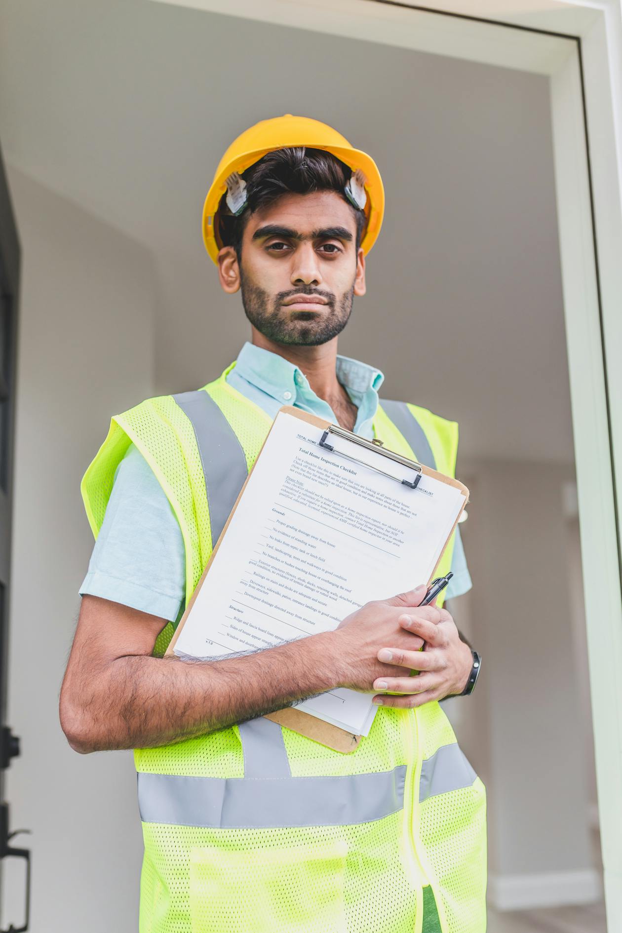 Construction inspector in yellow hard hat and high-visibility vest holding a documentation clipboard — 3D documentation of construction progress helps catch deviations from plans early