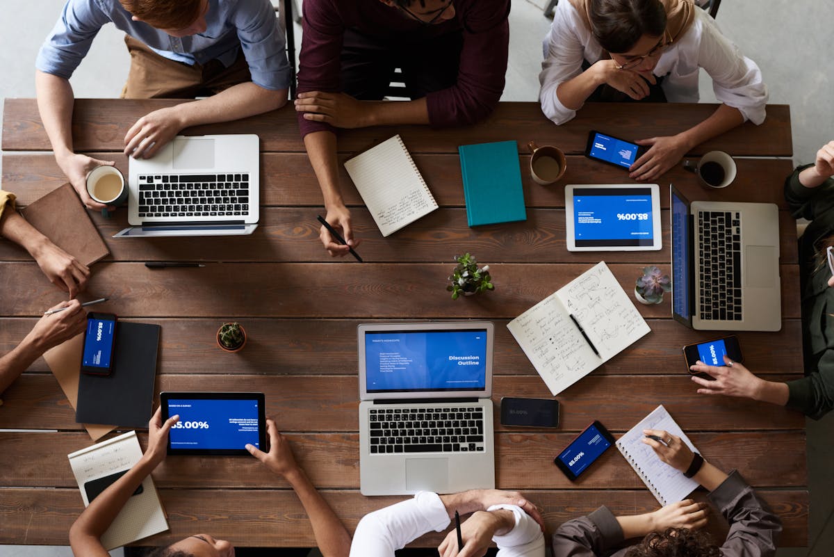 Overhead view of a team working together at a conference table with laptops and tablets