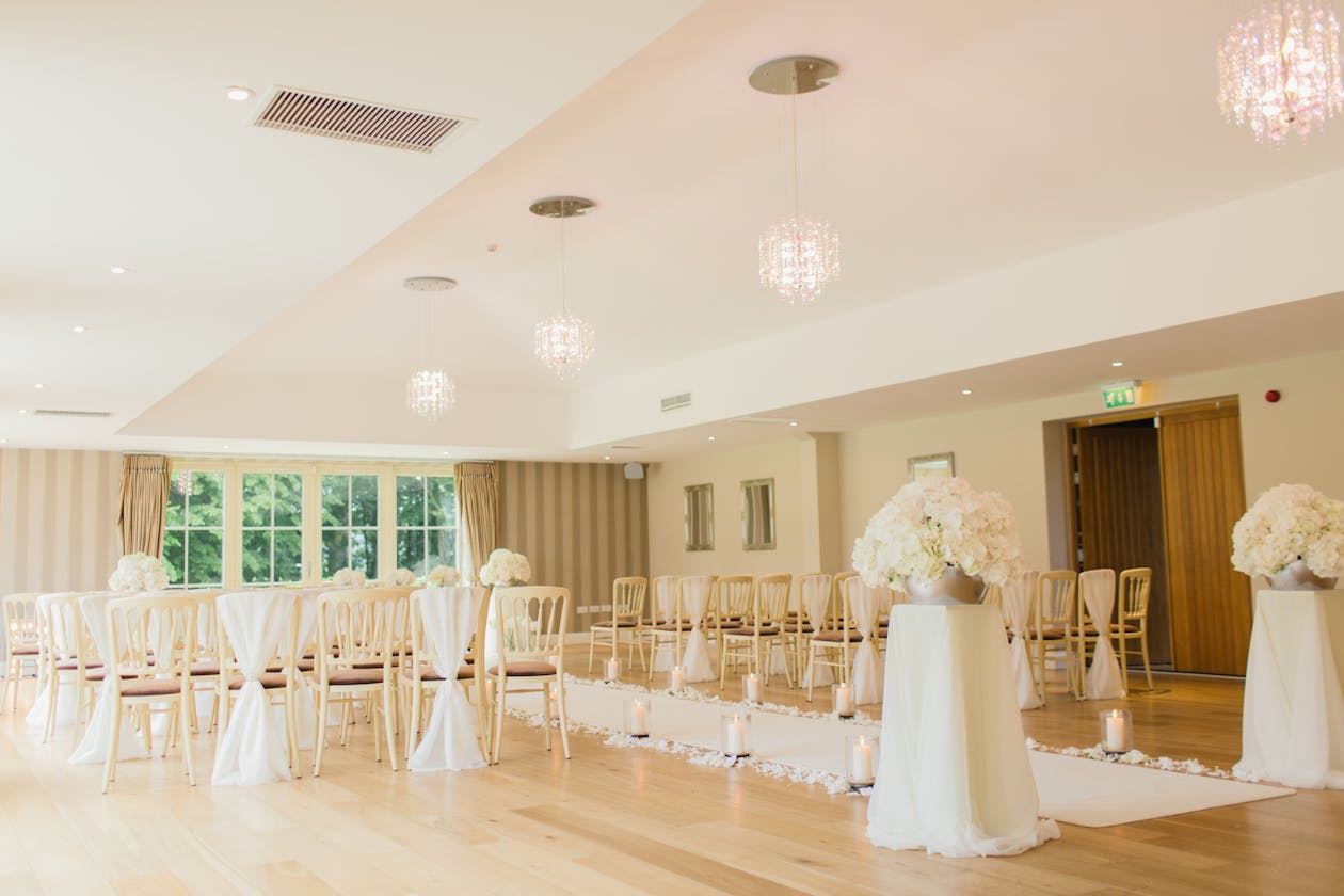 Elegant wedding venue ballroom with crystal chandeliers, white floral arrangements, and chiavari chairs — event venues see strong ROI from virtual tours because prospects who view the 3D tour convert at higher rates