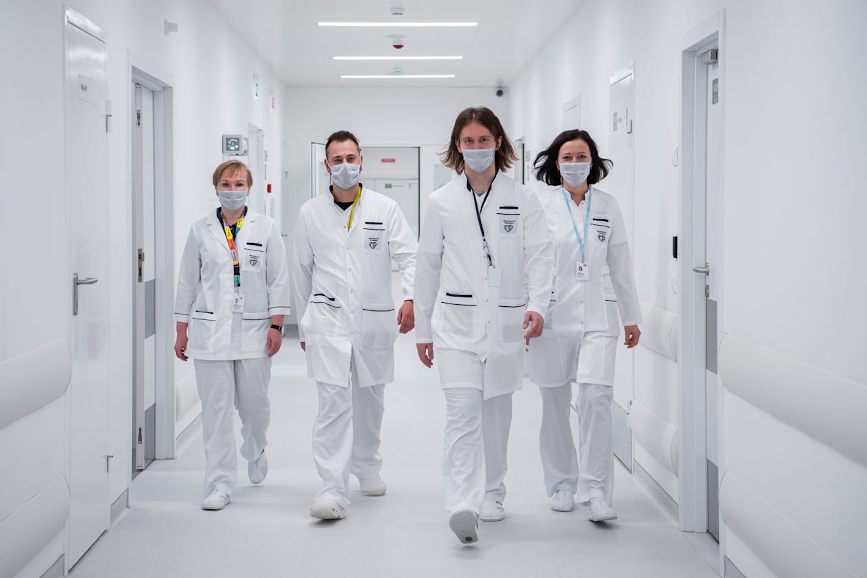 Medical team of four healthcare professionals walking through a modern white hospital corridor — healthcare facilities use virtual tours for patient orientation and facility marketing