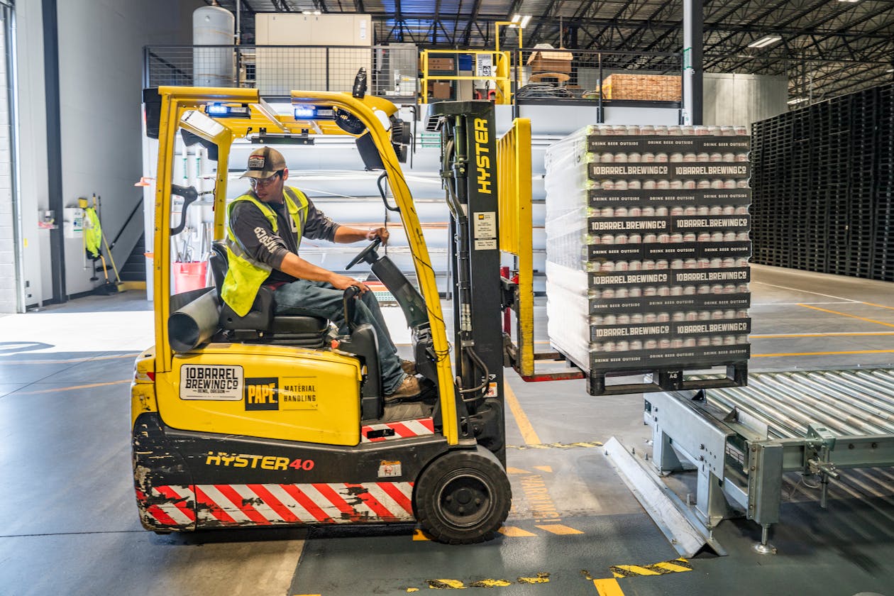 Forklift operator moving pallets inside a large warehouse facility — manufacturing and industrial facilities use 3D virtual tours for digital twins, safety training, and maintenance planning