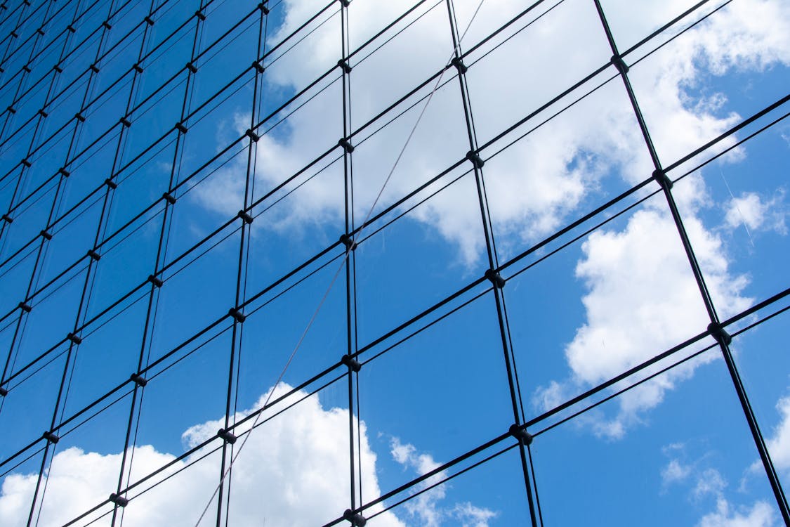 Modern glass facade reflecting blue sky — glass and reflective surfaces are a major challenge for 3D laser scanning