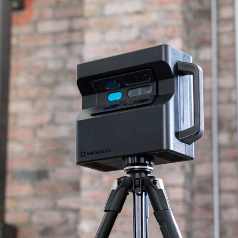 Matterport Pro2 camera set up on a tripod against a brick wall in an interior space