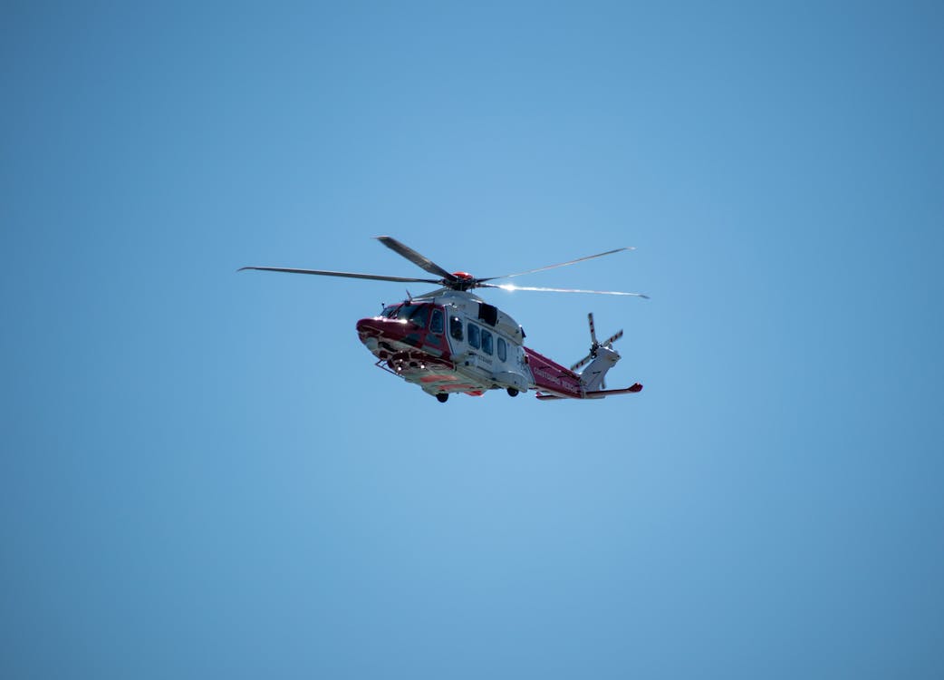 Red and white Coast Guard helicopter in flight against a clear blue sky