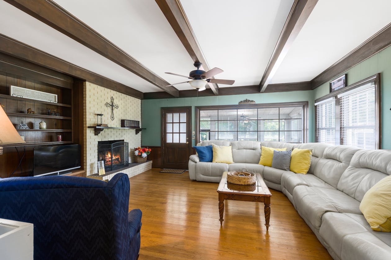 Spacious residential living room with classic American design, fireplace, exposed ceiling beams, and hardwood floors — a typical property that benefits from residential virtual tours