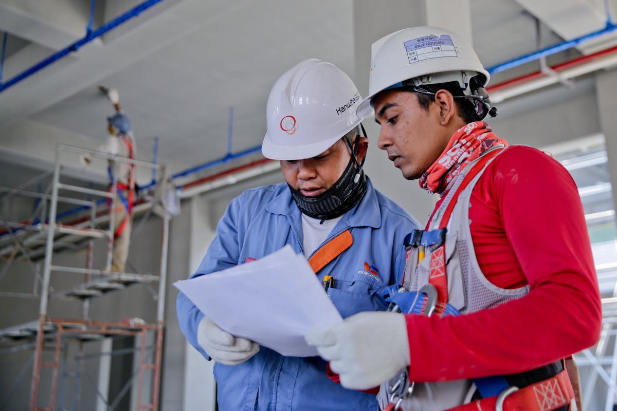 Construction workers in hard hats reviewing project documents at a building site