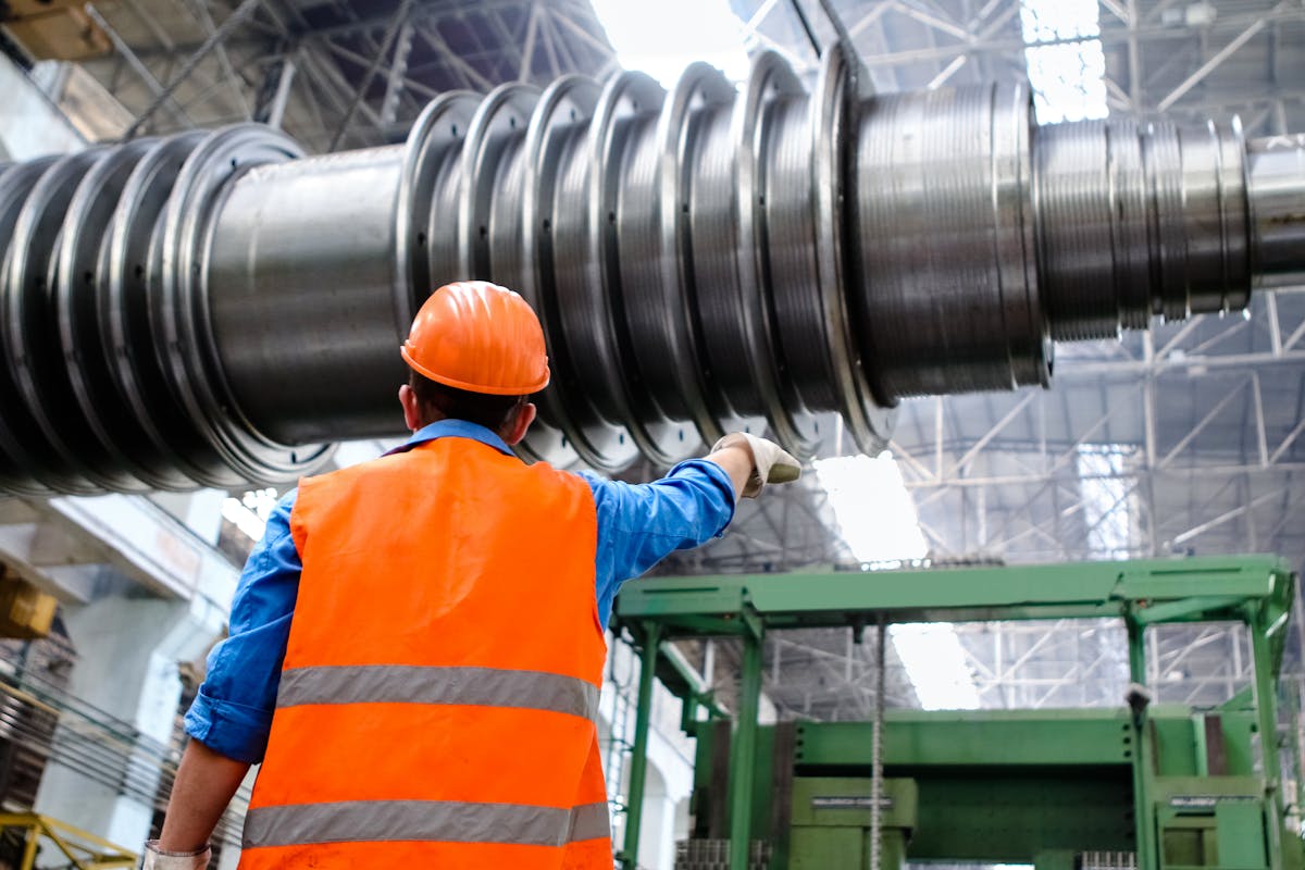 Industrial worker inspecting large machinery in a manufacturing facility
