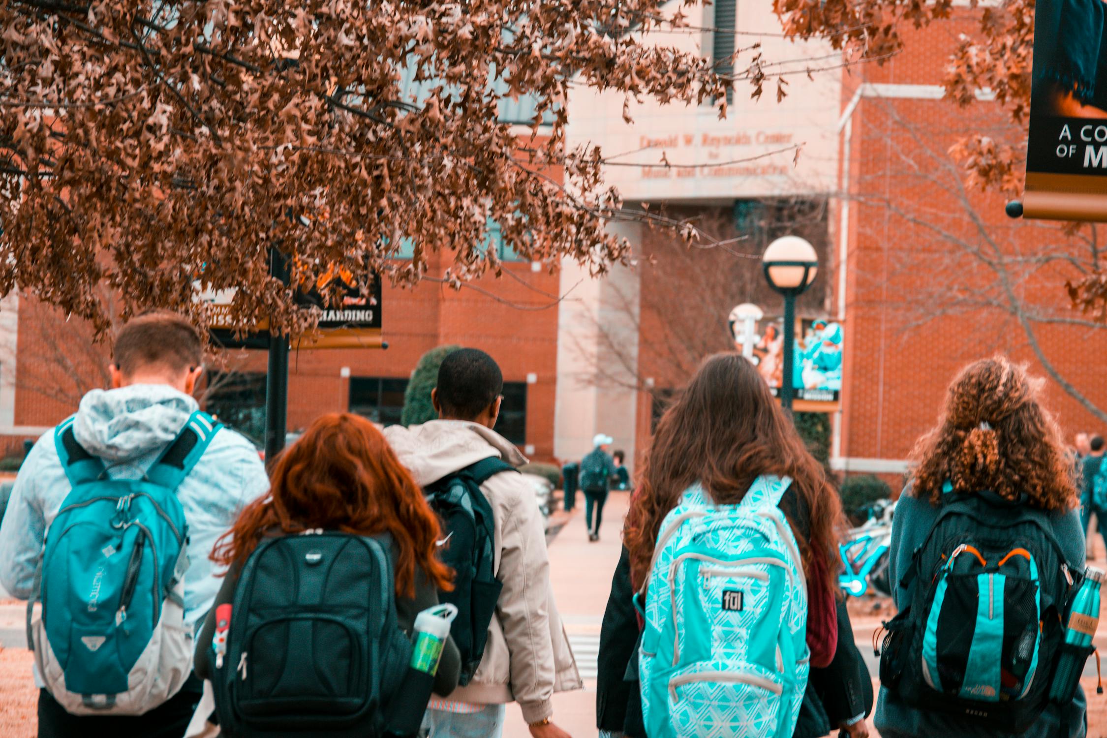 Group of students with backpacks walking together toward campus building