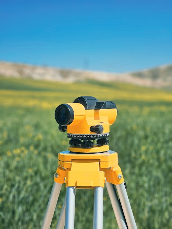 Yellow survey equipment on tripod in an open field for land measurement