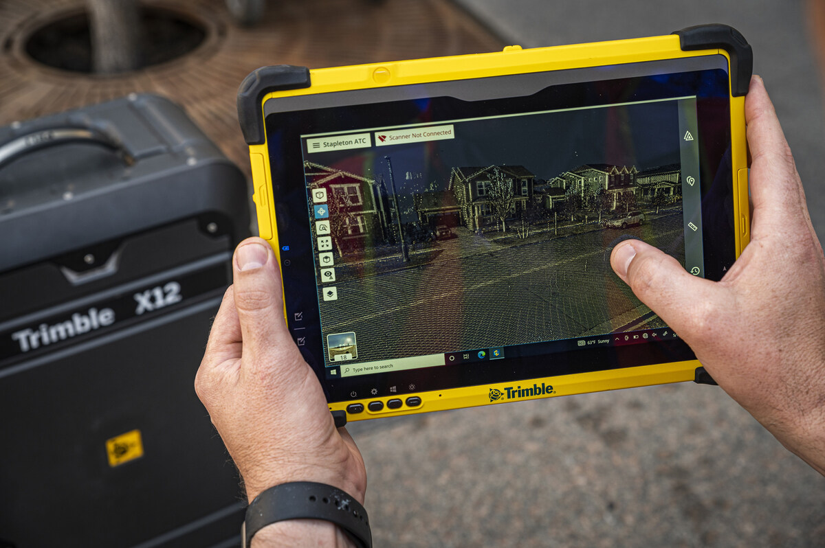 Trimble X12 3D laser scanner field tablet displaying a colorized point cloud of a neighborhood